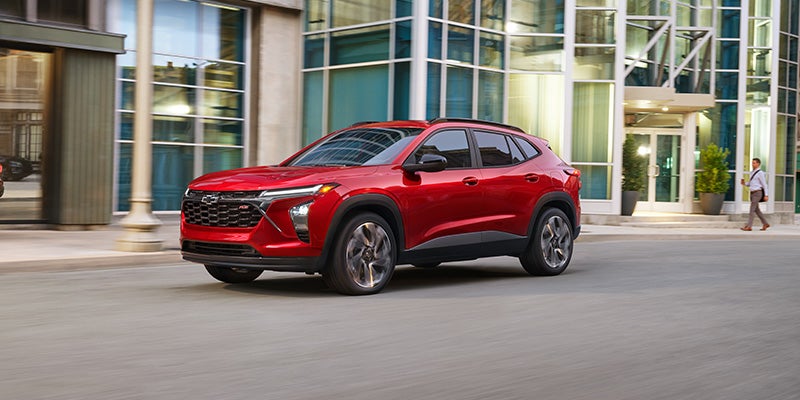 A Chevrolet Trax driving along a bustling city street, showcasing its sleek design and urban environment.